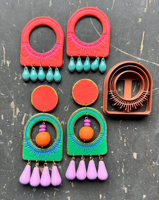 Colorful statement earrings with bold geometric shapes and dangling beads beside brown polymer clay cutters from THERETRODOLLHOUSE creations
