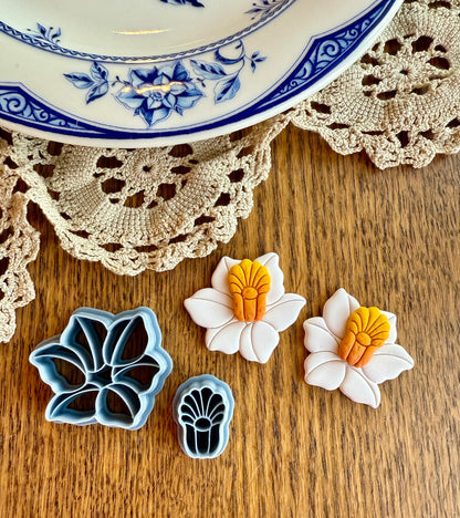 Daffodil Builder clay cutter set next to daffodil-shaped clay pieces on a wooden surface.